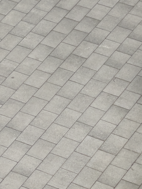 Grau gepflasterter Boden aus gleichmäßig angeordneten Platten.